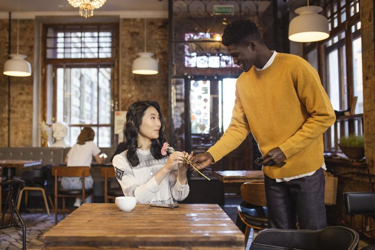 Pareja cruzando miradas en una cafetería, atracción de sinastría Venus conjunción Ascendente