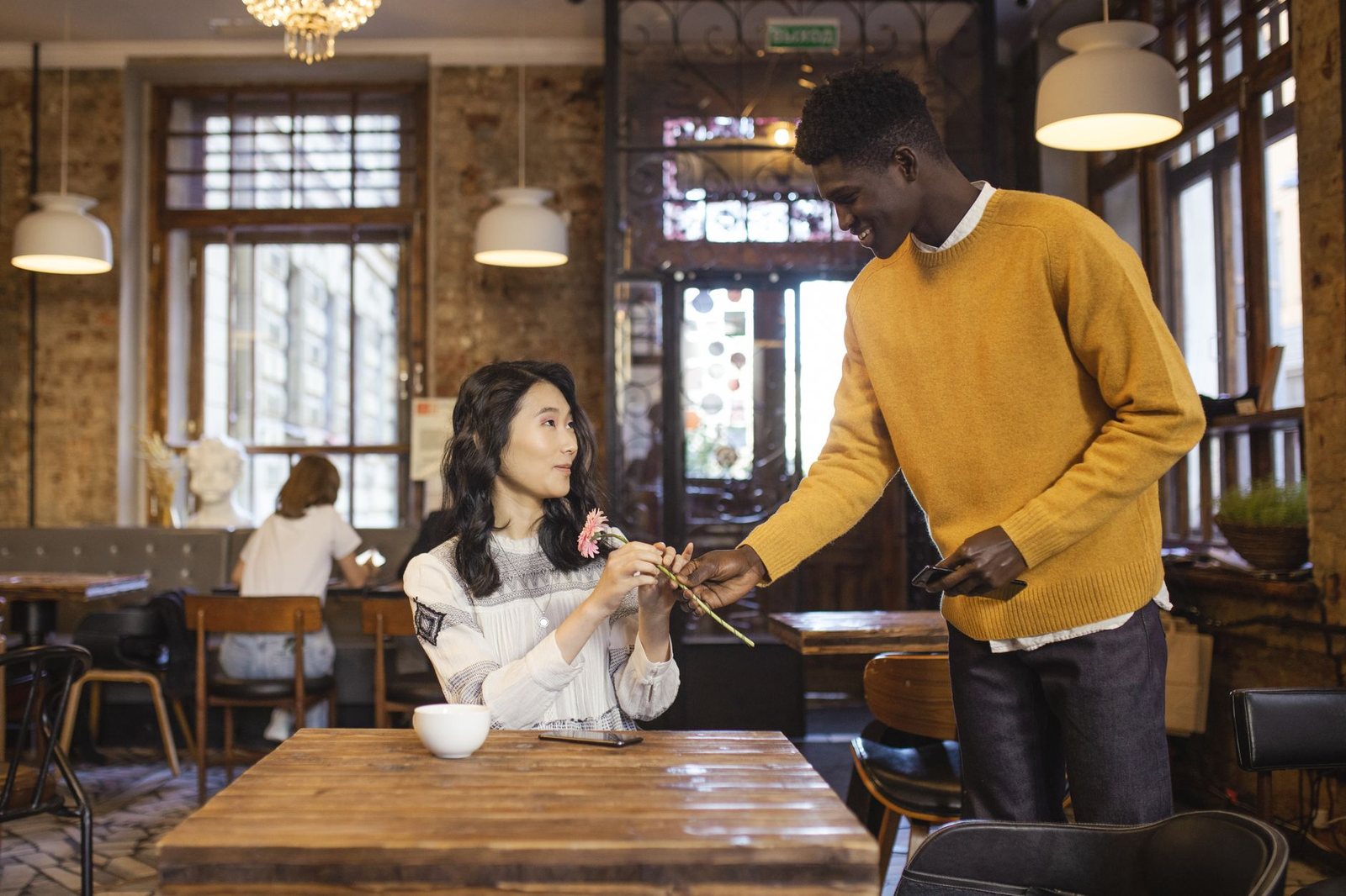 Pareja cruzando miradas en una cafetería, atracción de sinastría Venus conjunción Ascendente