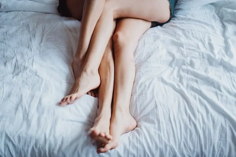 Acuario y Cáncer en la cama: química y deseo real Pareja abrazada entre sábanas blancas que evoca a Acuario y Cáncer en la cama