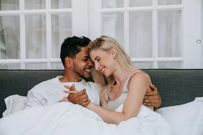 Acuario y Libra en la cama: química, deseo y complicidad Pareja riendo en la cama, reflejo de la complicidad de Acuario y Libra en la cama