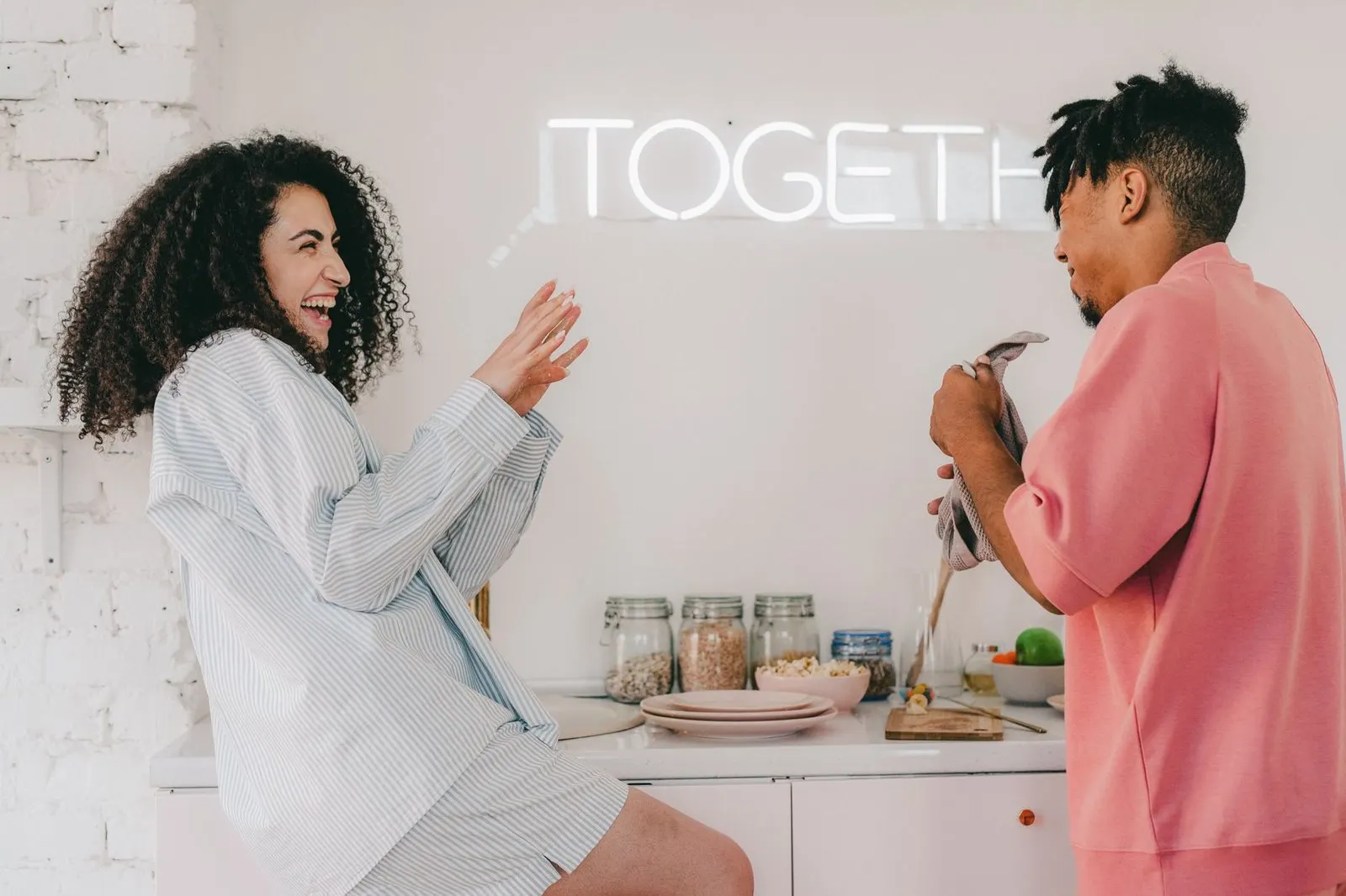 Pareja riendo en la cocina, reflejo de la afinidad cotidiana entre signos del zodiaco