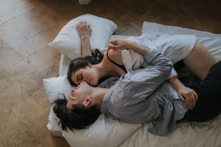 Pareja abrazada en la habitación al atardecer, química de Aries y Acuario en la cama