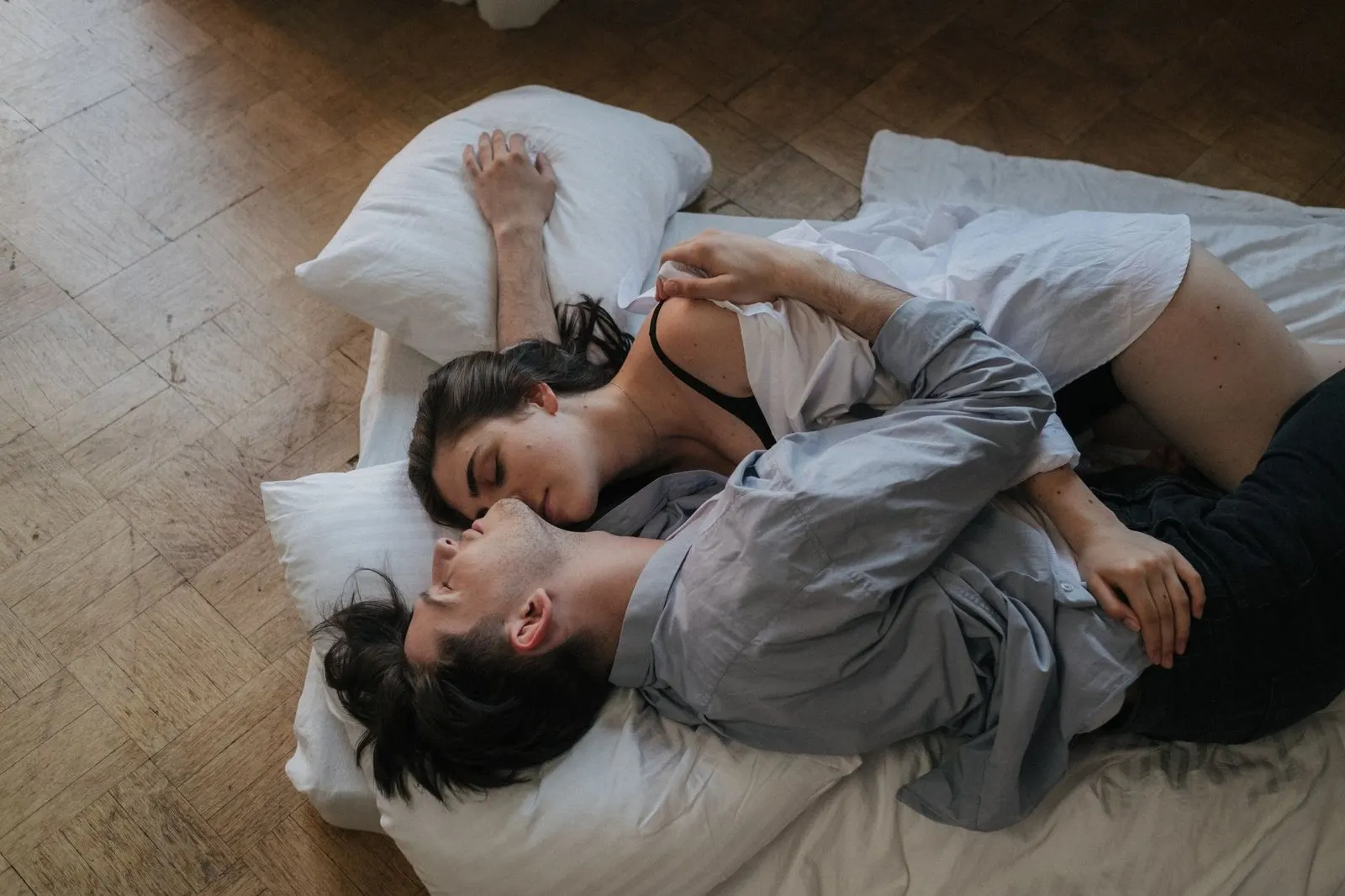 Pareja abrazada en la habitación al atardecer, química de Aries y Acuario en la cama