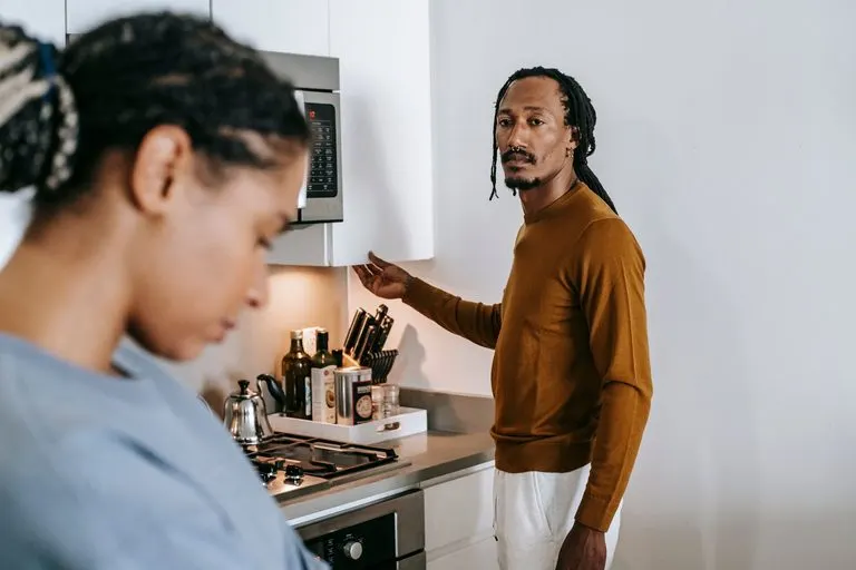 Aries celoso: cómo son sus celos y cómo manejarlos Pareja con una conversación tensa en la cocina, reflejo de un aries celoso