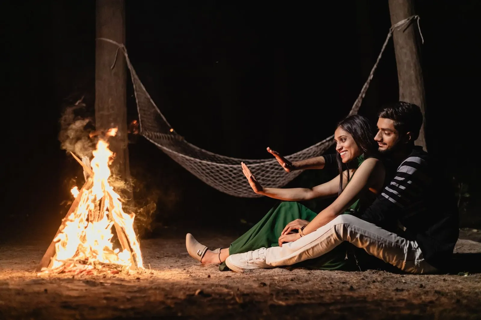 Pareja abrazada junto a una hoguera nocturna, símbolo del amor de fuego de Aries