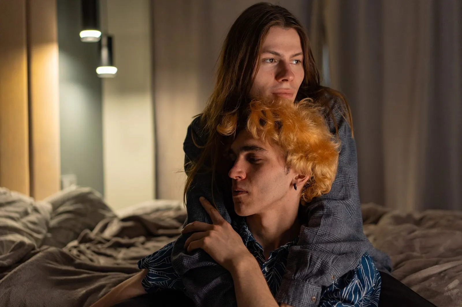 Pareja abrazada con luz cálida, símbolo de Aries y Géminis en la cama