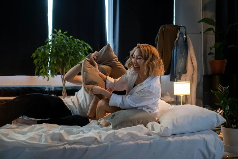 Pareja riendo en la cama, reflejo de la química entre Aries y Géminis