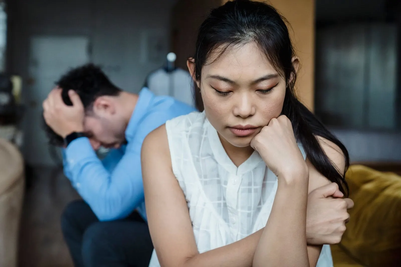 Pareja sentada en silencio en el sofá con distancia emocional tras discutir