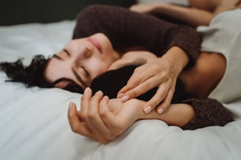 Pareja abrazada en la cama con luz suave, química entre Capricornio y Tauro