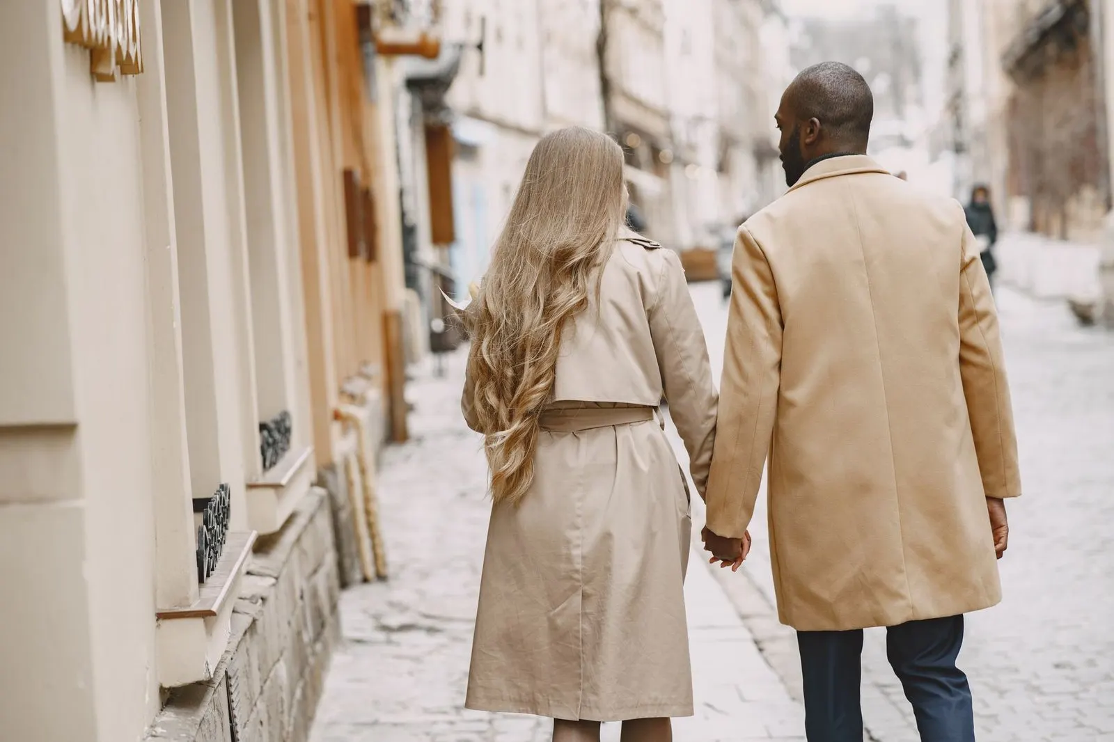 Hombre tomando la mano de su pareja por la calle con gesto protector