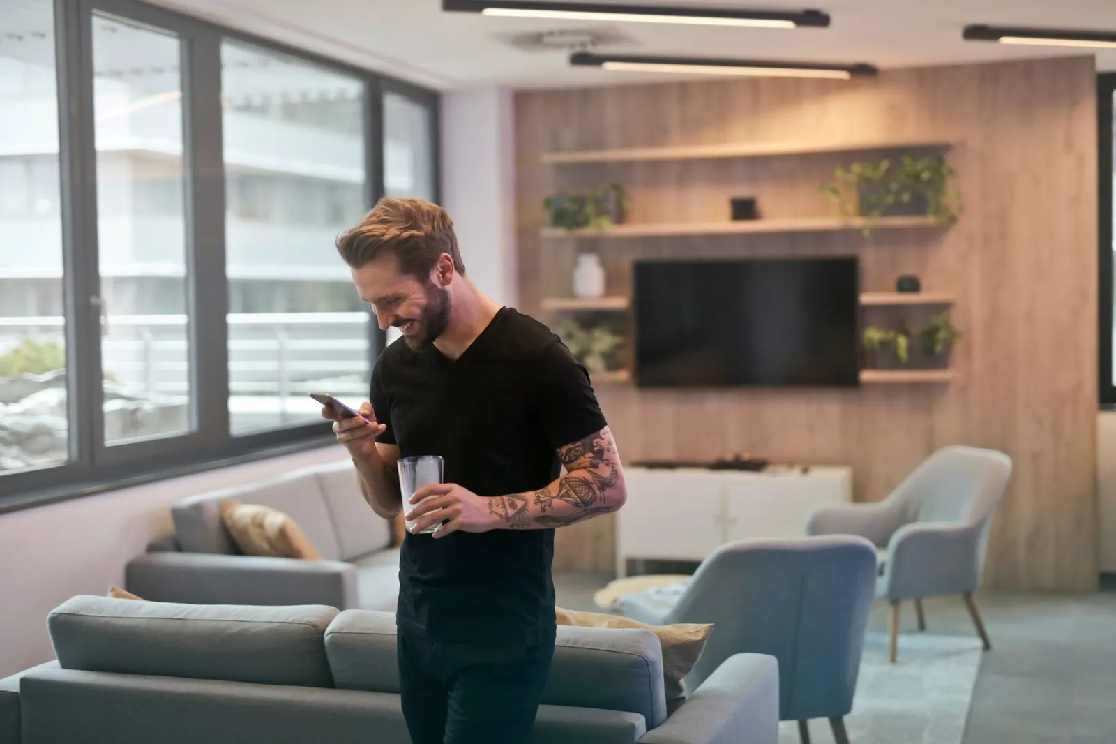 Hombre Géminis riendo al leer un mensaje de WhatsApp en su teléfono