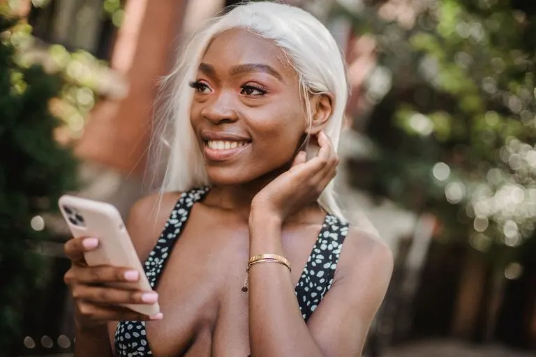 Cómo conquistar a un Géminis por mensajes y WhatsApp Mujer sonriendo mientras escribe en el móvil para conquistar a un Géminis por mensajes