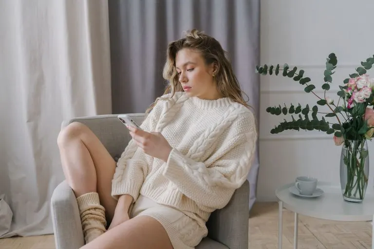 Mujer escribiendo en el móvil en casa para conquistar a un Tauro por mensajes