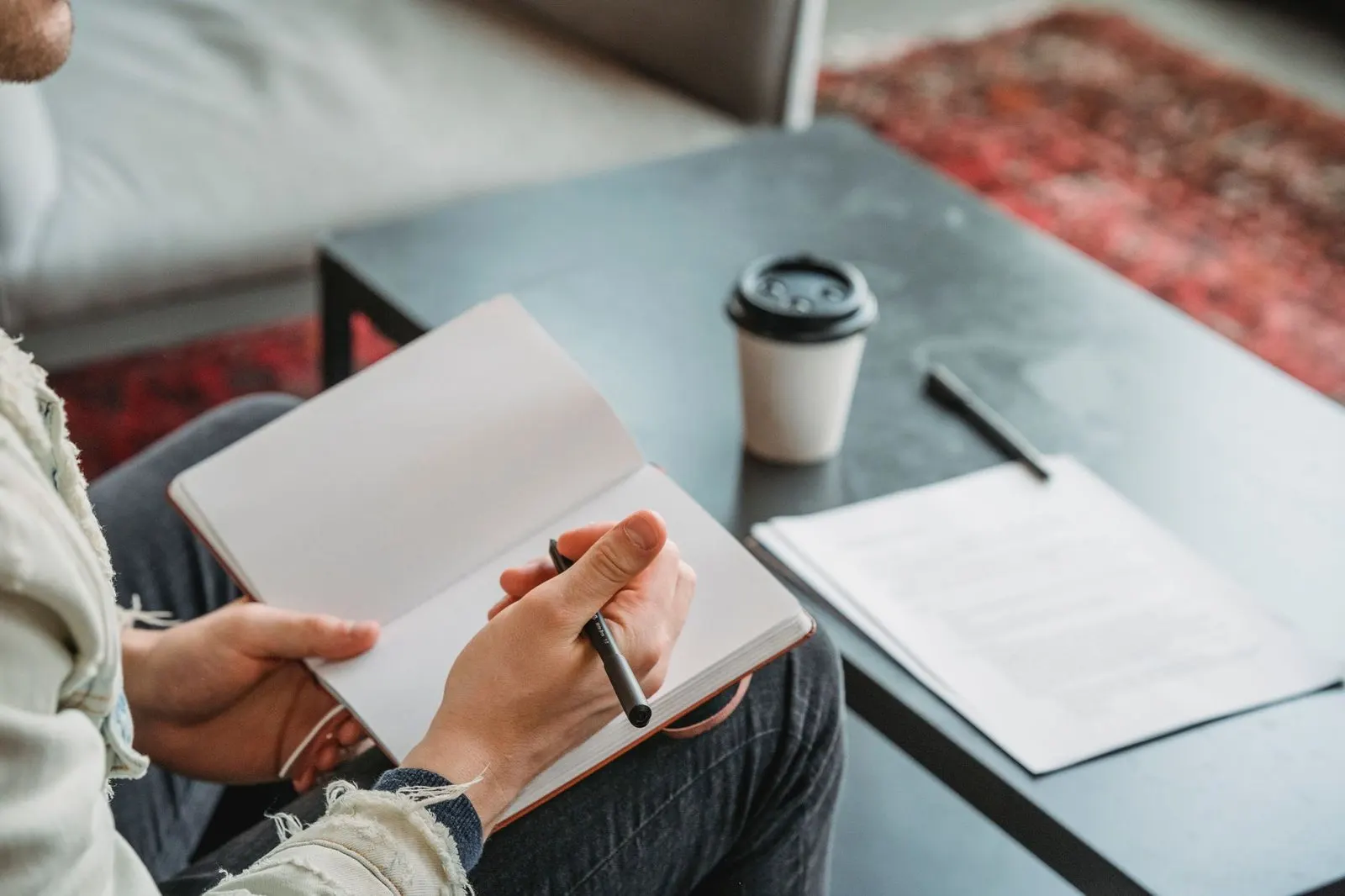 Manos ordenando una agenda junto a un café, detalle y rutina compartida en pareja