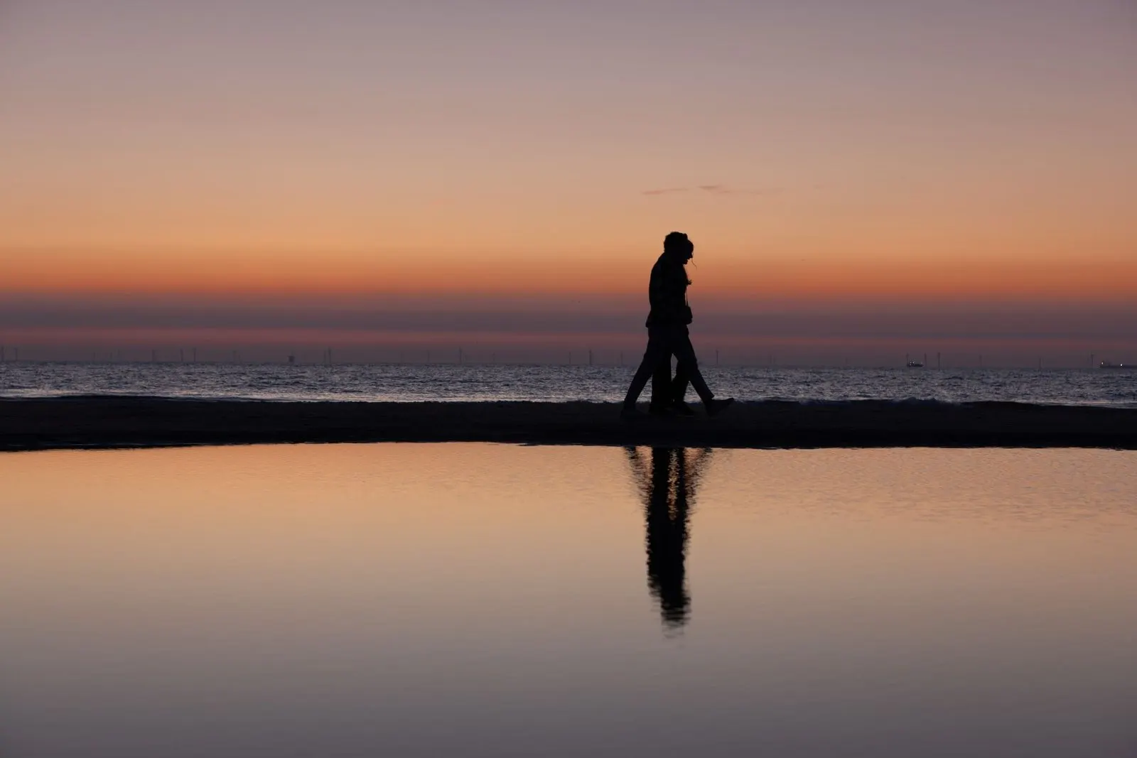 Pareja paseando por la orilla del mar al anochecer, símbolo del amor entre signos de agua