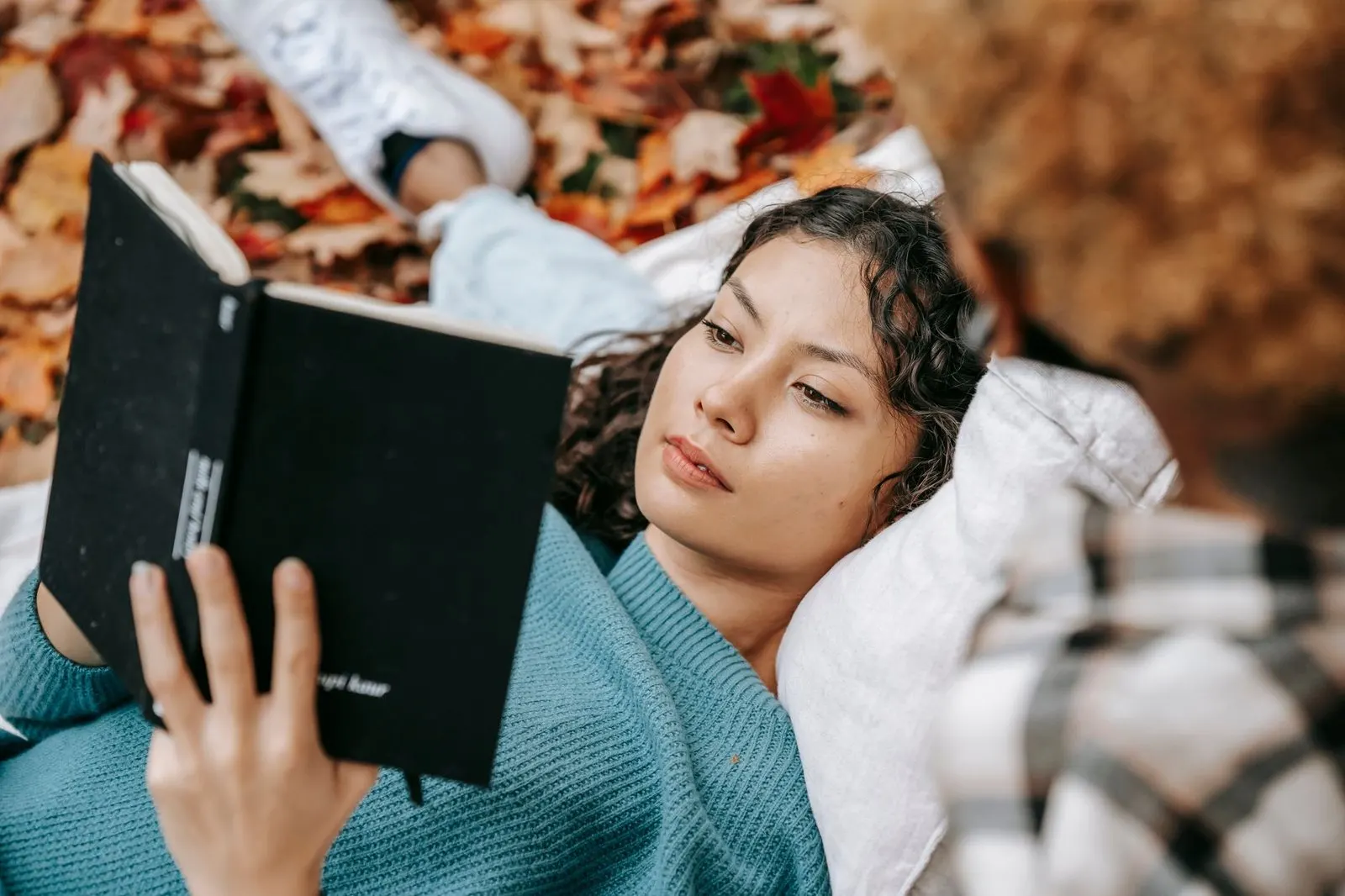 Dos personas leyendo libros juntas en un parque, complicidad intelectual entre signos de aire