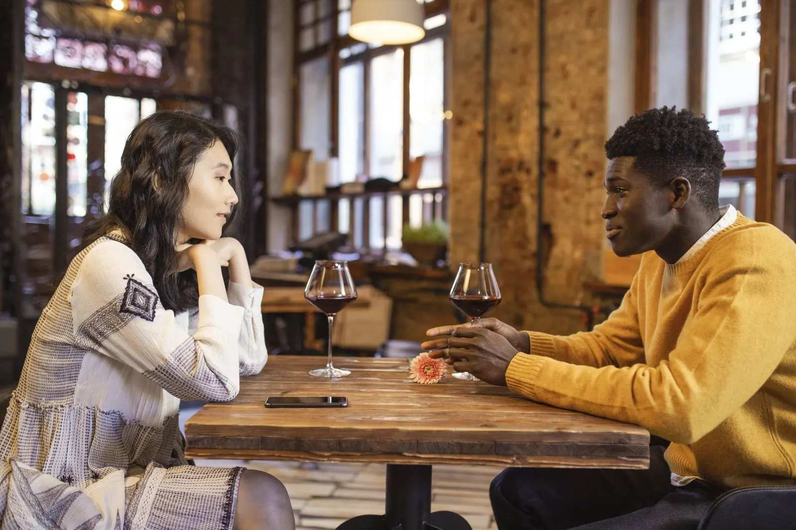 Dos personas conversan animadas en una cafetería, Acuario y Leo en el amor