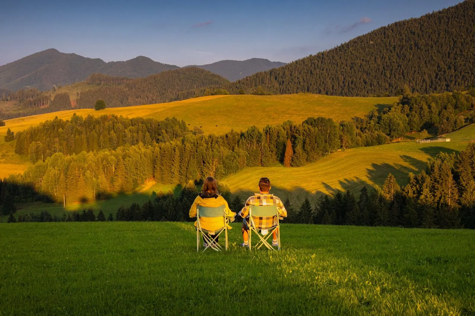 Hombre y mujer caminando juntos por la montaña al atardecer compartiendo una aventura