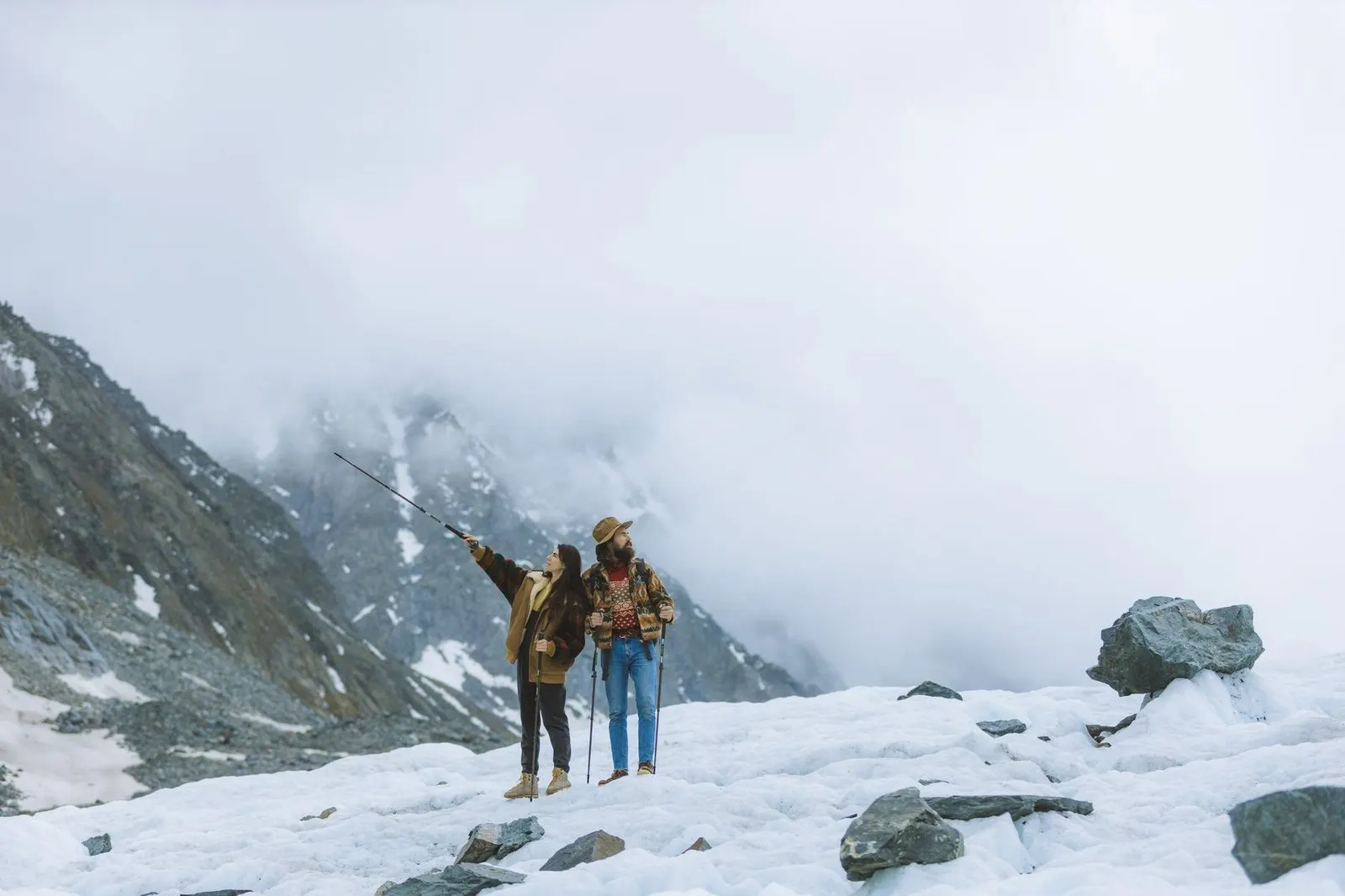 Mujer aventurera en la montaña mientras su pareja la observa con calma