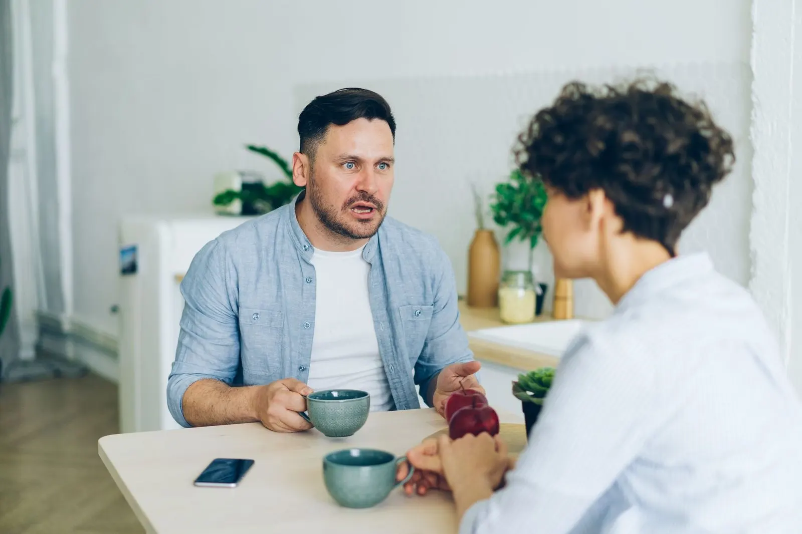 Mujer Escorpio y hombre Cáncer conversando tranquilos en la cocina de casa