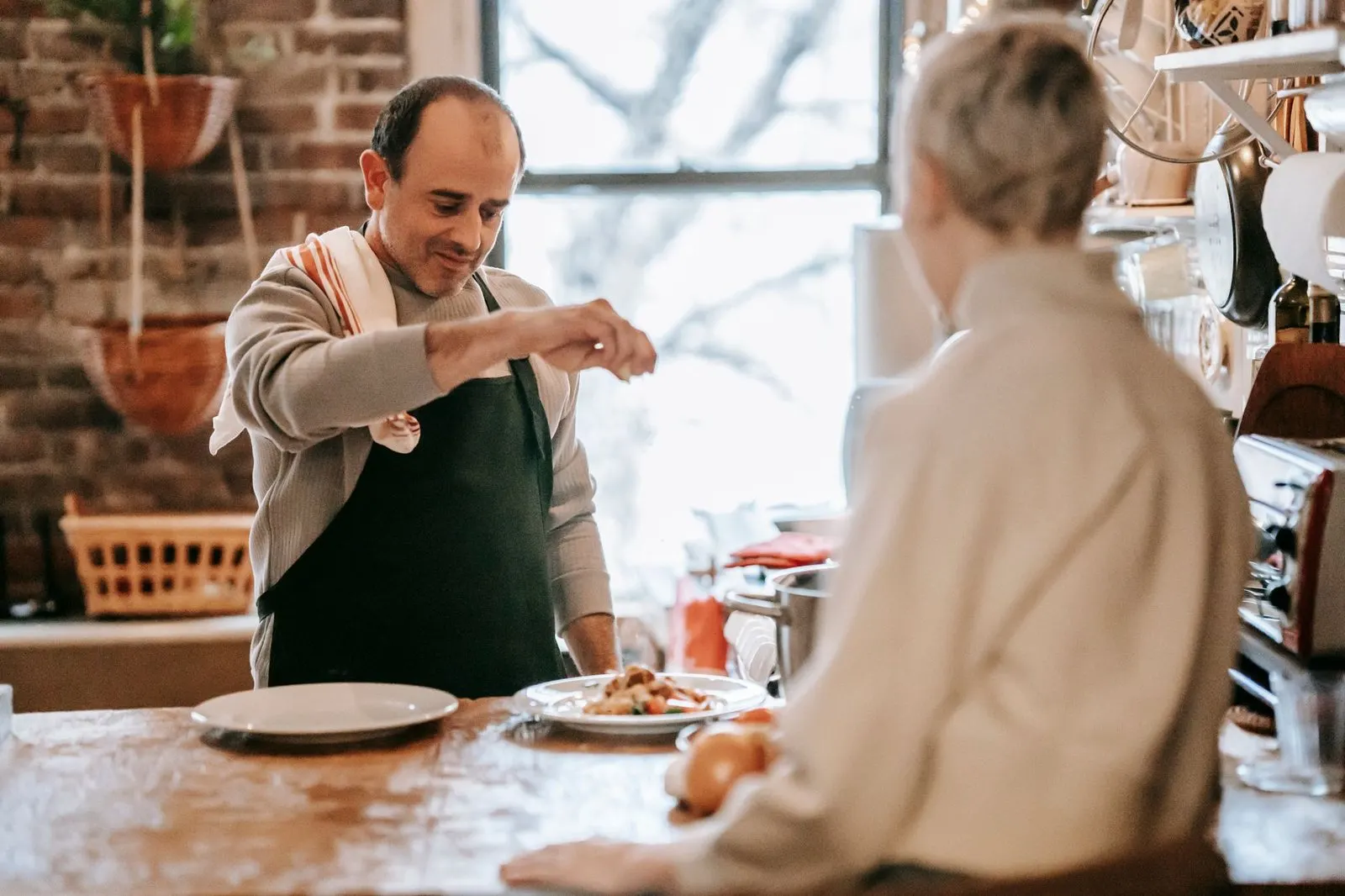 Hombre preparando la cena en casa mientras su pareja le cuenta su día