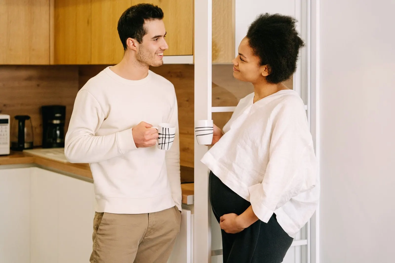 Pareja conversando en una cocina acogedora, símbolo de convivencia entre Cáncer y Piscis