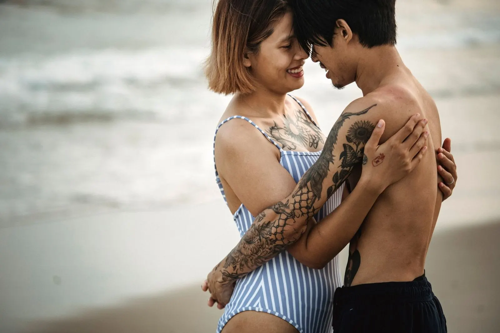 Hombre Cáncer y mujer Piscis abrazados con ternura frente al mar al atardecer