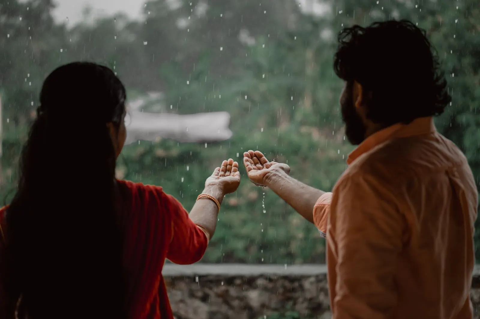 Manos entrelazadas junto a una ventana con lluvia, ternura y calma en pareja