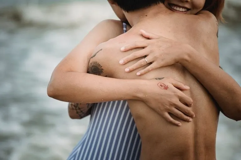 Hombre Escorpio y mujer Cáncer abrazados frente al mar al atardecer