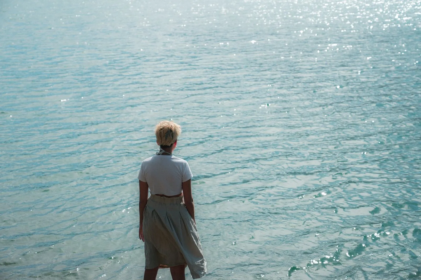 Mujer pensativa contemplando el agua en calma, evocando la sensibilidad de Piscis