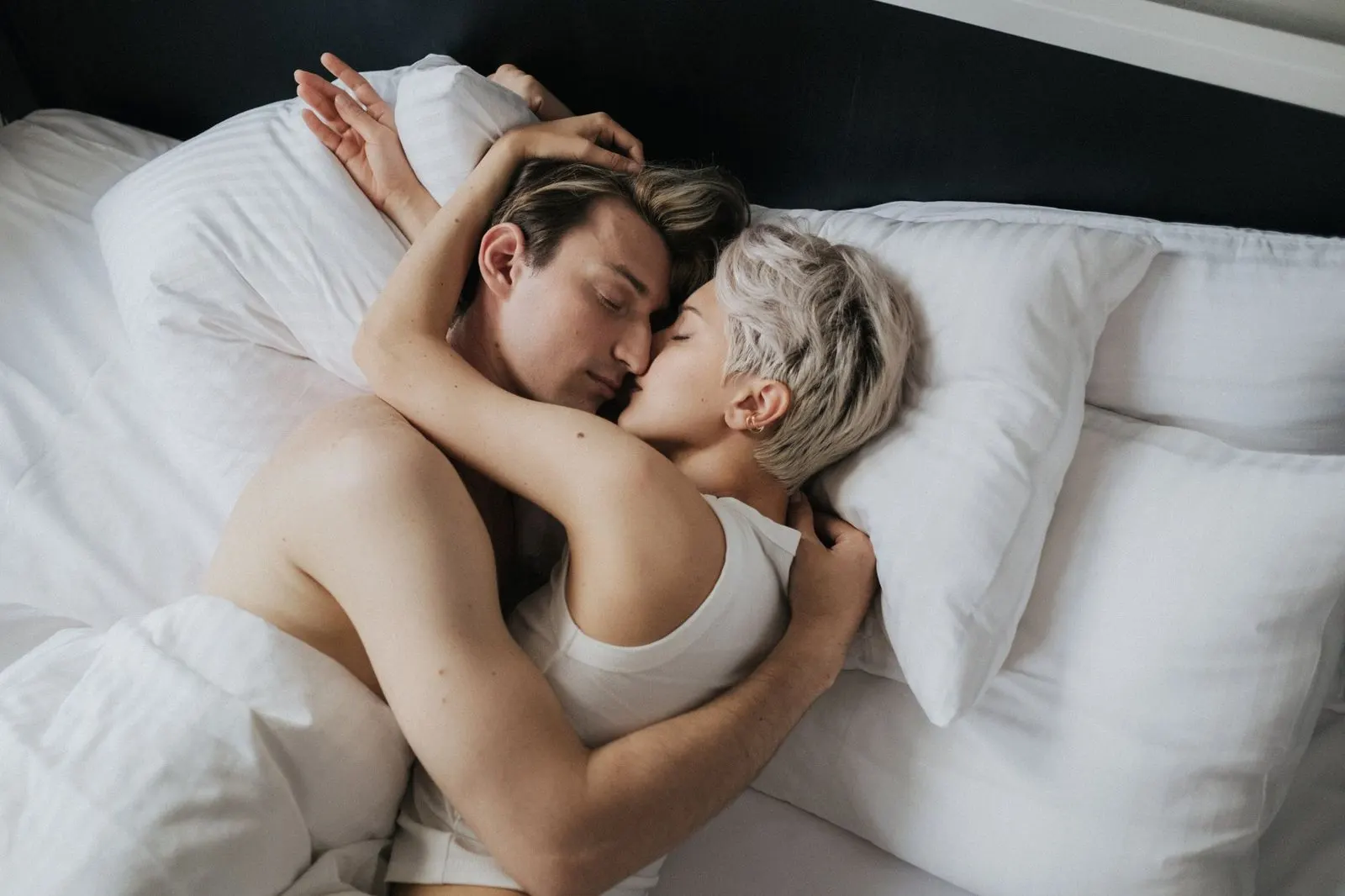 Pareja abrazada en la cama por la mañana, reflejo de la intimidad entre Leo y Virgo