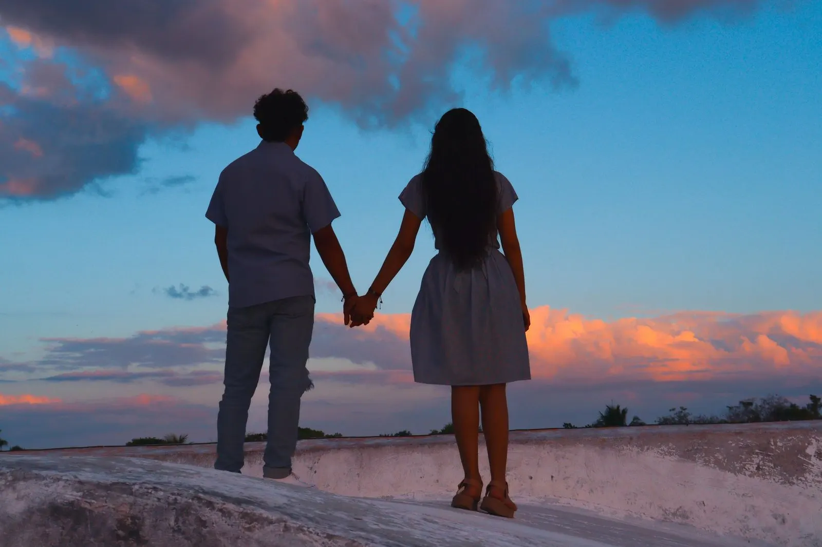 Hombre Libra y mujer Aries cogidos de la mano al atardecer
