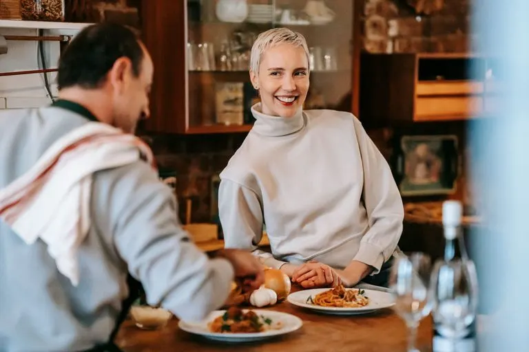 Hombre Libra y mujer Aries riendo juntos durante una cena romántica