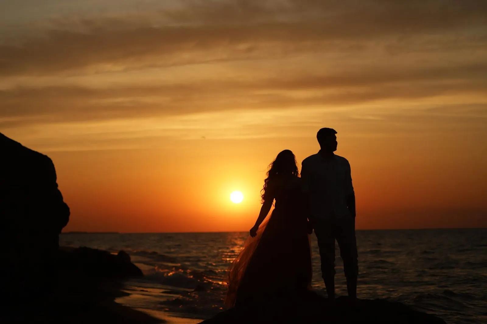 Hombre Libra y mujer Piscis abrazados frente al mar al atardecer
