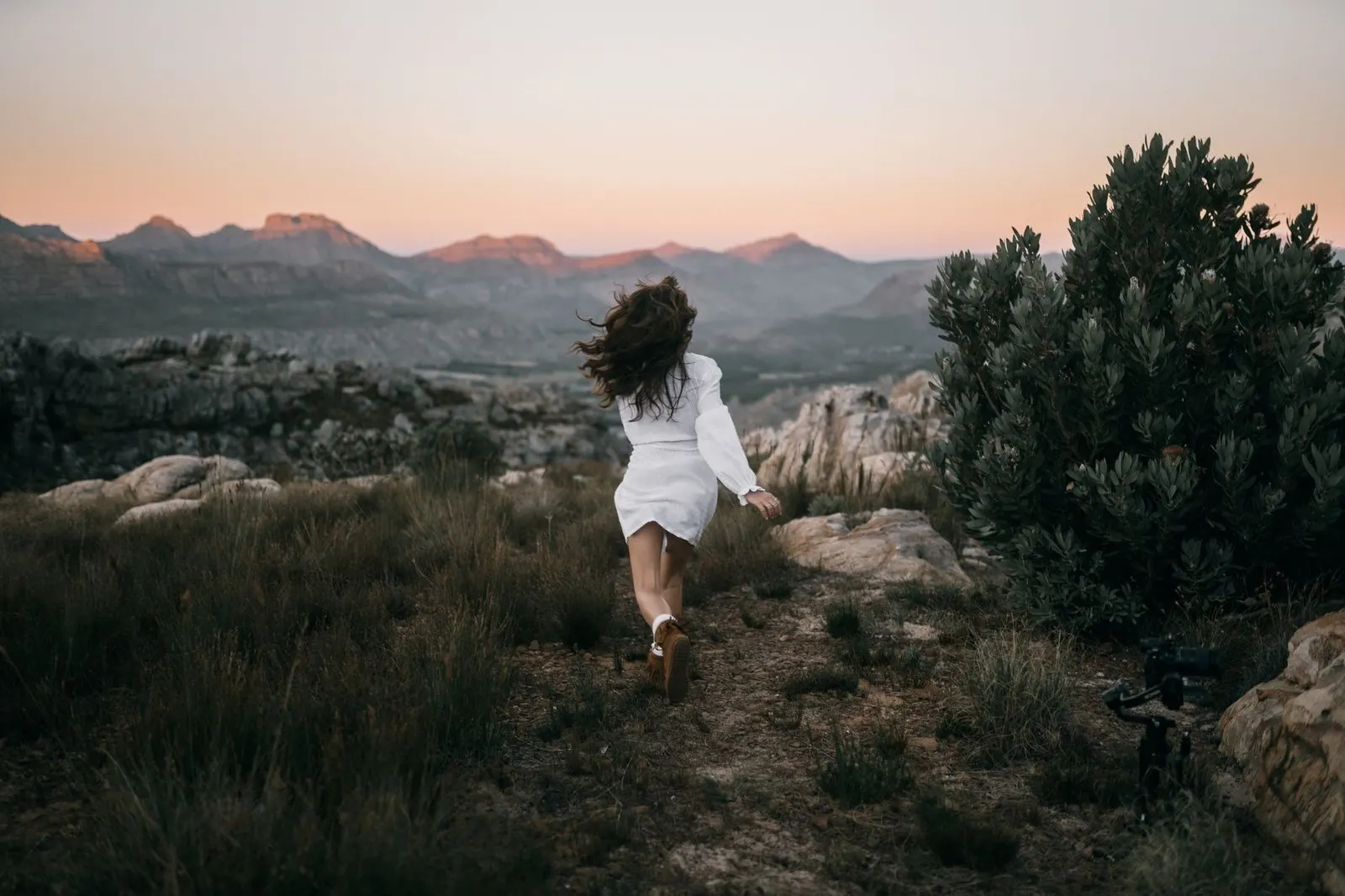 Mujer Sagitario caminando por la montaña al atardecer con espíritu libre y aventurero