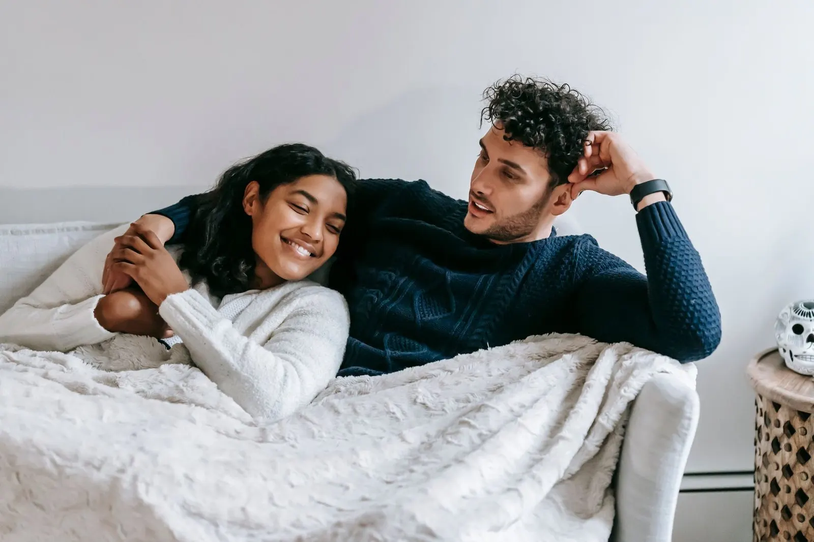 Pareja abrazada bajo una manta en el sofá, ternura y confianza compartida