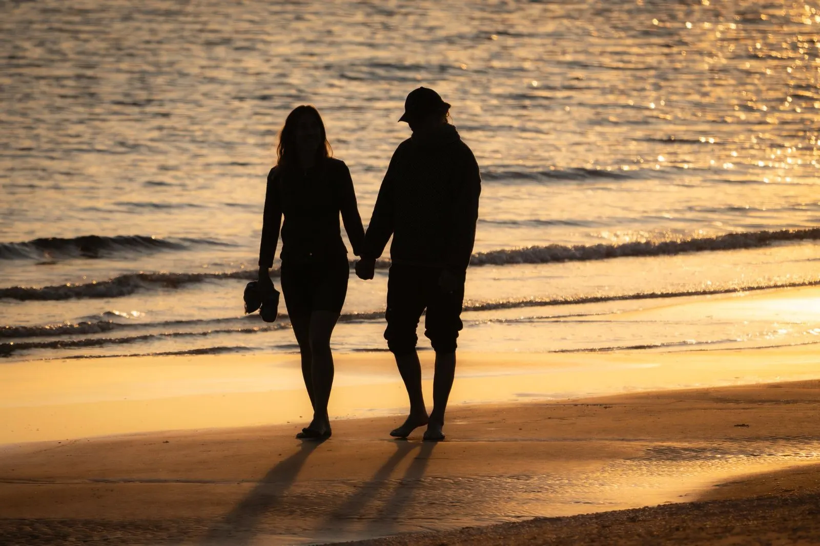 Pareja paseando por la orilla del mar al atardecer, símbolo de Virgo y Piscis
