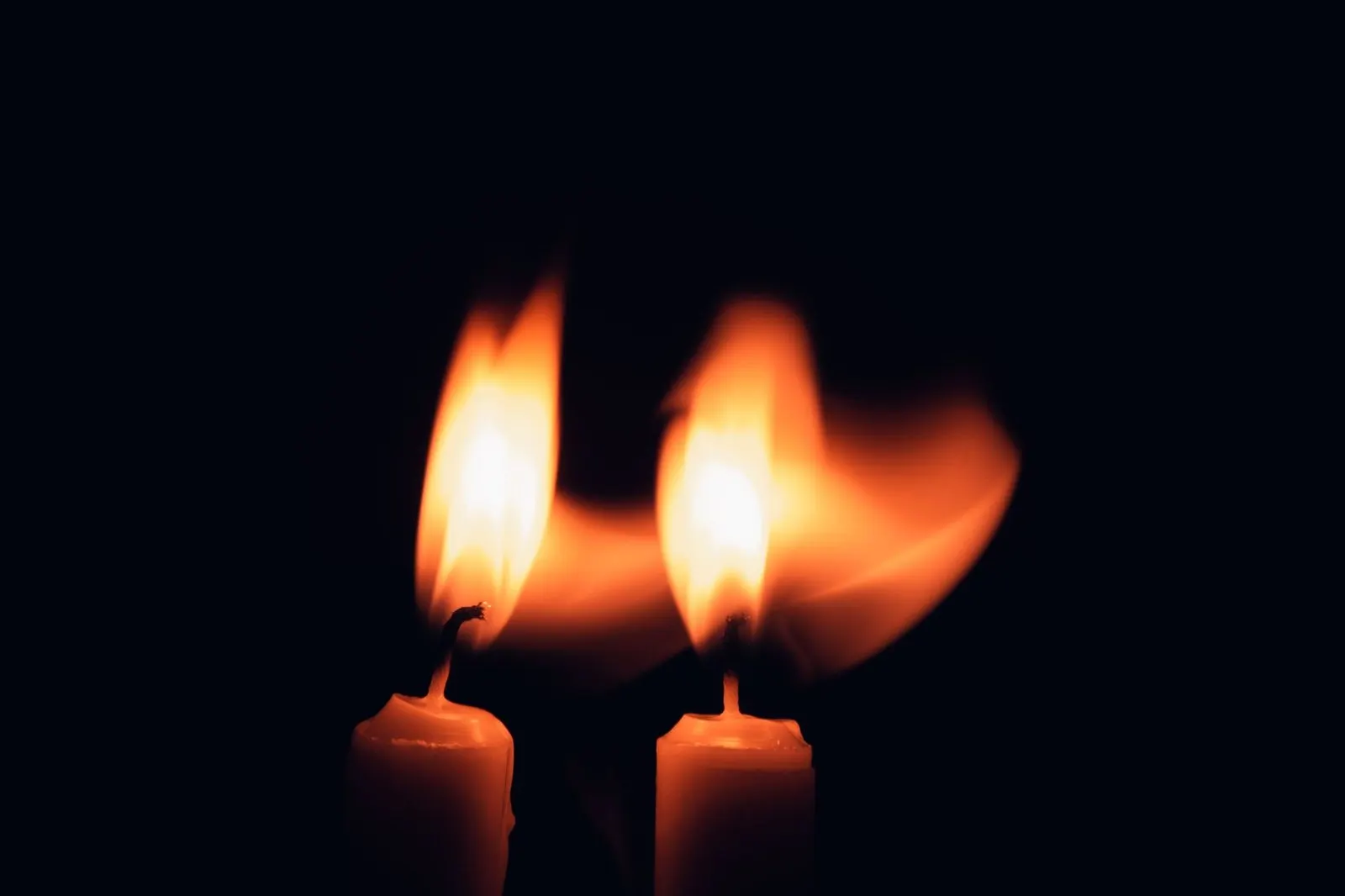 Dos llamas de vela encendidas juntas en la oscuridad como símbolo de llama gemela