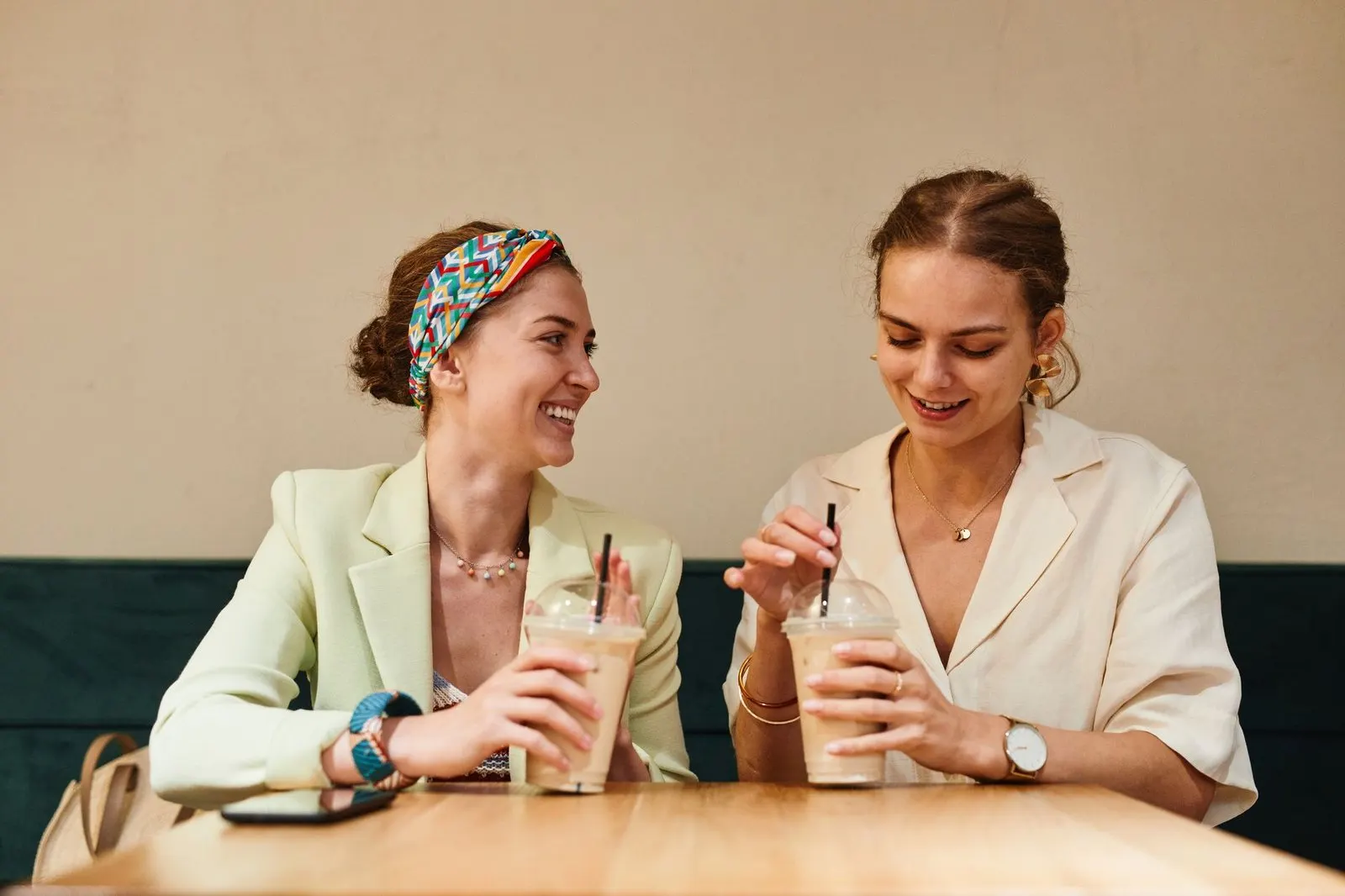Dos amigas conversando y riendo en una cafetería, energía emocional de la Luna en Géminis
