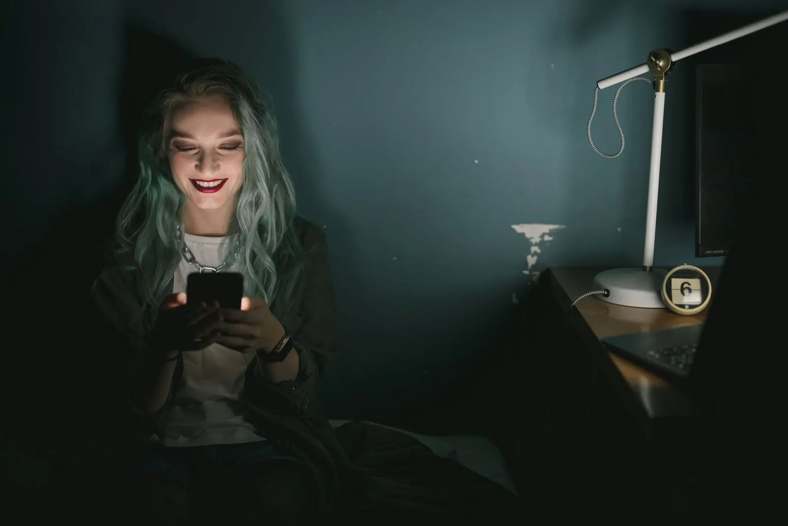 Mujer sonriendo mientras escribe mensajes en el móvil por la noche, seducción con palabras