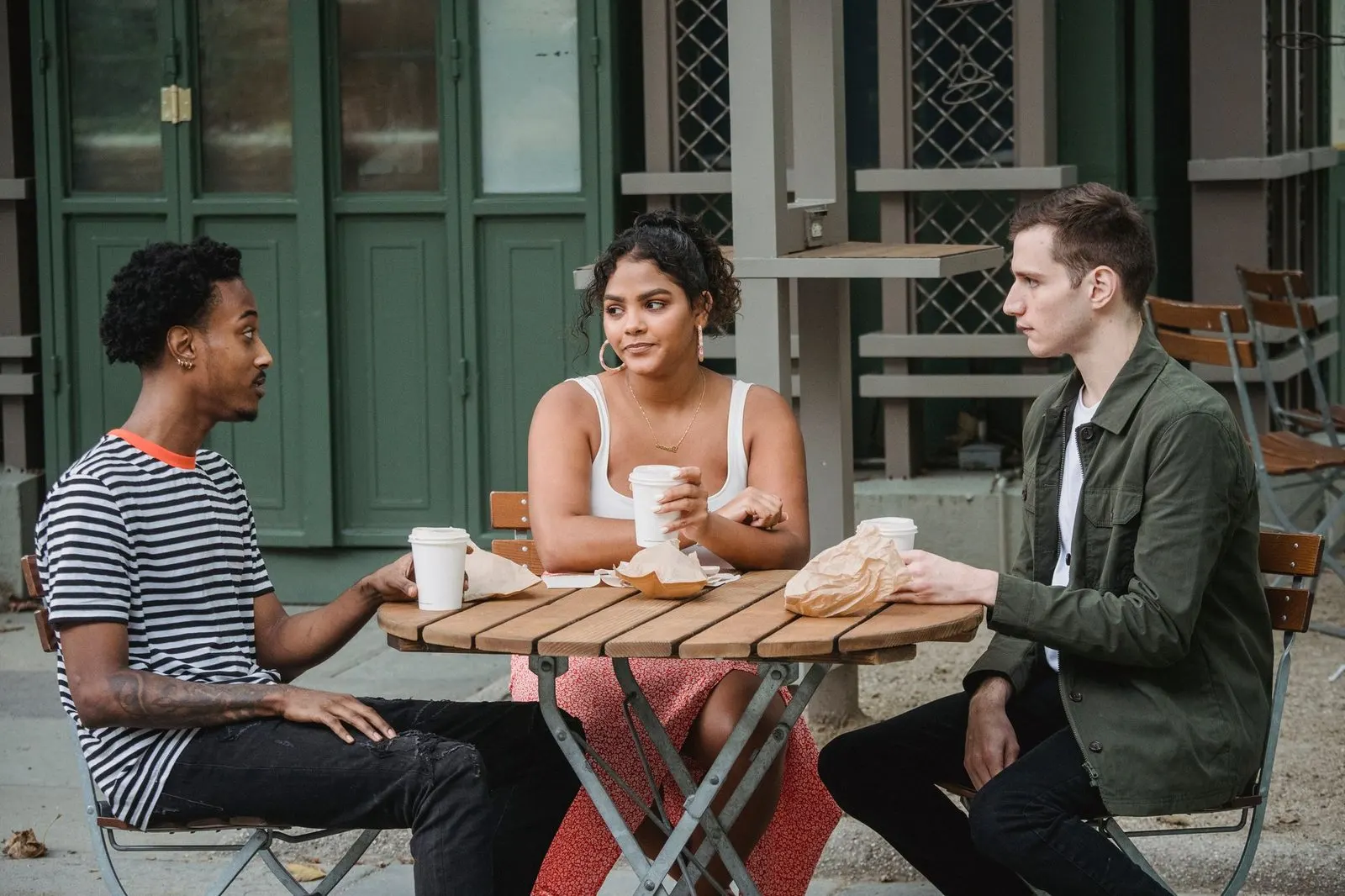 Amigos debatiendo con entusiasmo en la mesa de un café, energía curiosa de Marte en Géminis