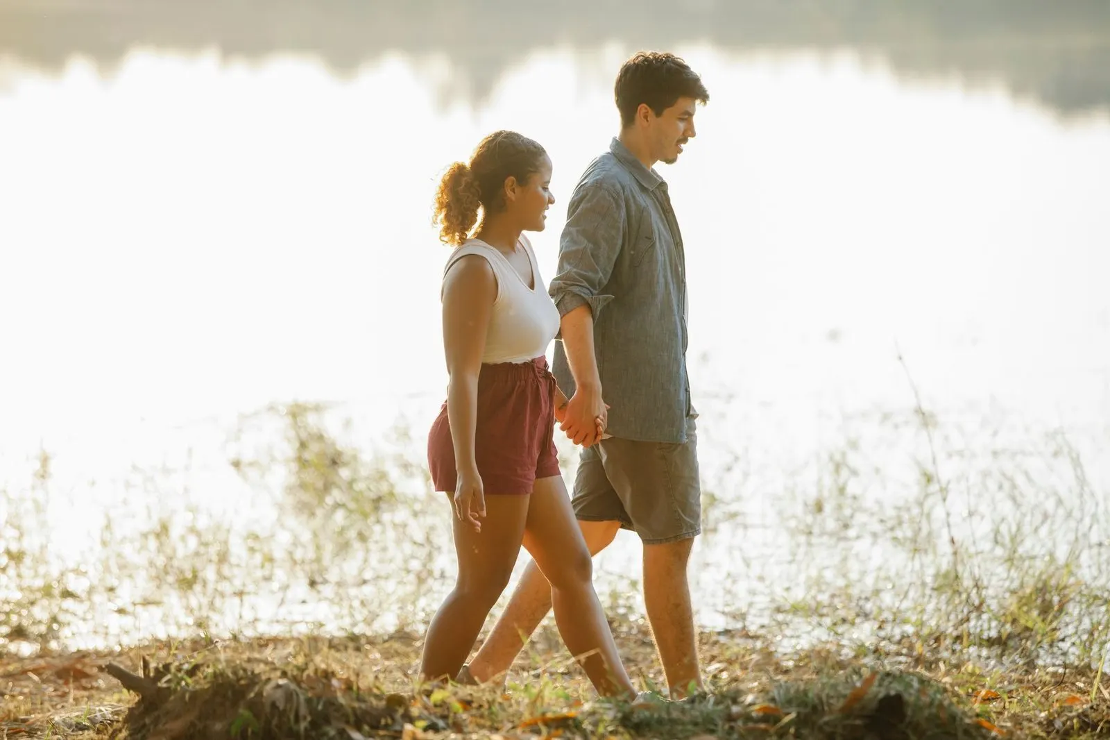 Manos entrelazadas de una pareja en el campo, símbolo de calma y constancia