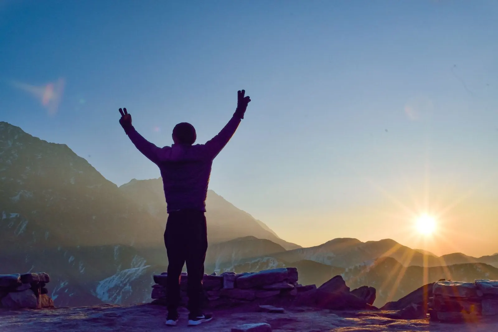 Mujer en la cima de una montaña al amanecer, símbolo del nodo norte en Aries