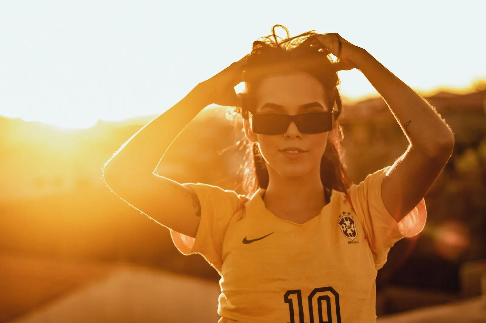 Mujer sonriendo bajo la luz dorada del atardecer, reflejo del Nodo Norte en Leo