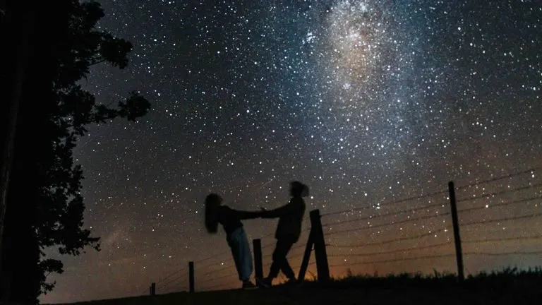 Porcentaje de compatibilidad signos: qué mide y qué no Pareja mirando el cielo nocturno y pensando en su porcentaje de compatibilidad entre signos