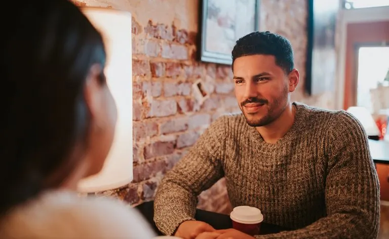Cómo recuperar a un Aries: qué funciona y qué no Pareja conversando en una cafetería, reflejo de cómo recuperar a un Aries