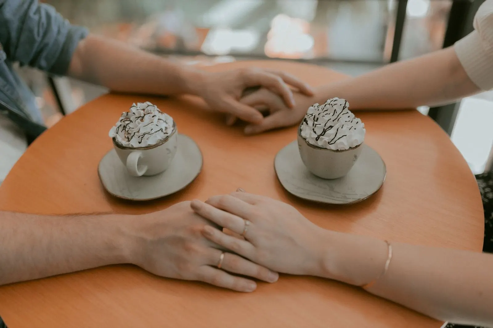 Pareja cogida de la mano en una cafetería, gesto típico de un Tauro que te quiere