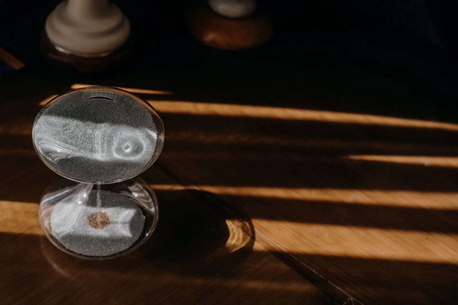 Reloj de arena sobre una mesa de madera que evoca el tiempo y Saturno