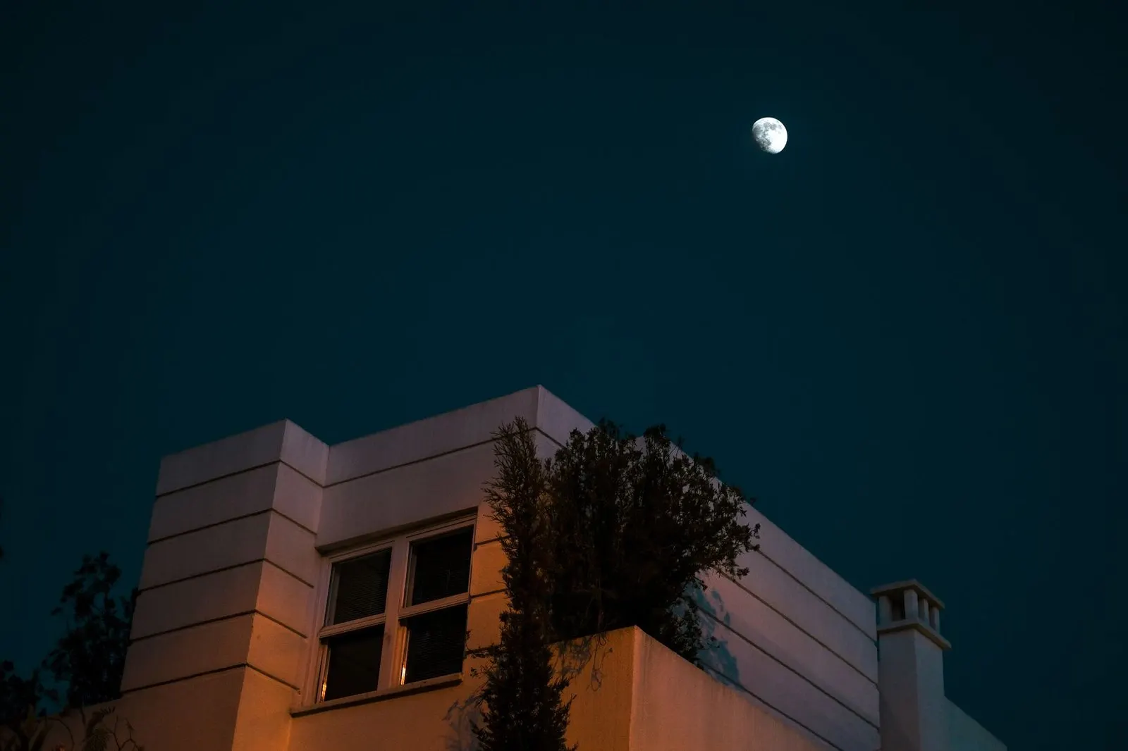 Luna llena sobre una casa iluminada, símbolo del refugio emocional en pareja