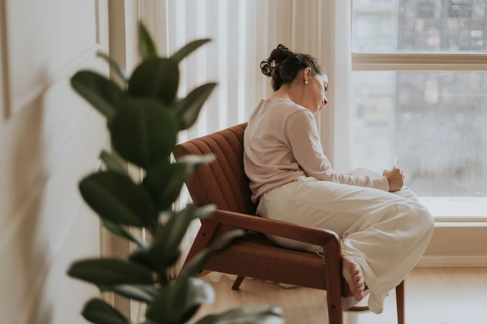 Mujer escribiendo junto a la ventana reflexionando sobre Venus en casa 12 en sinastría